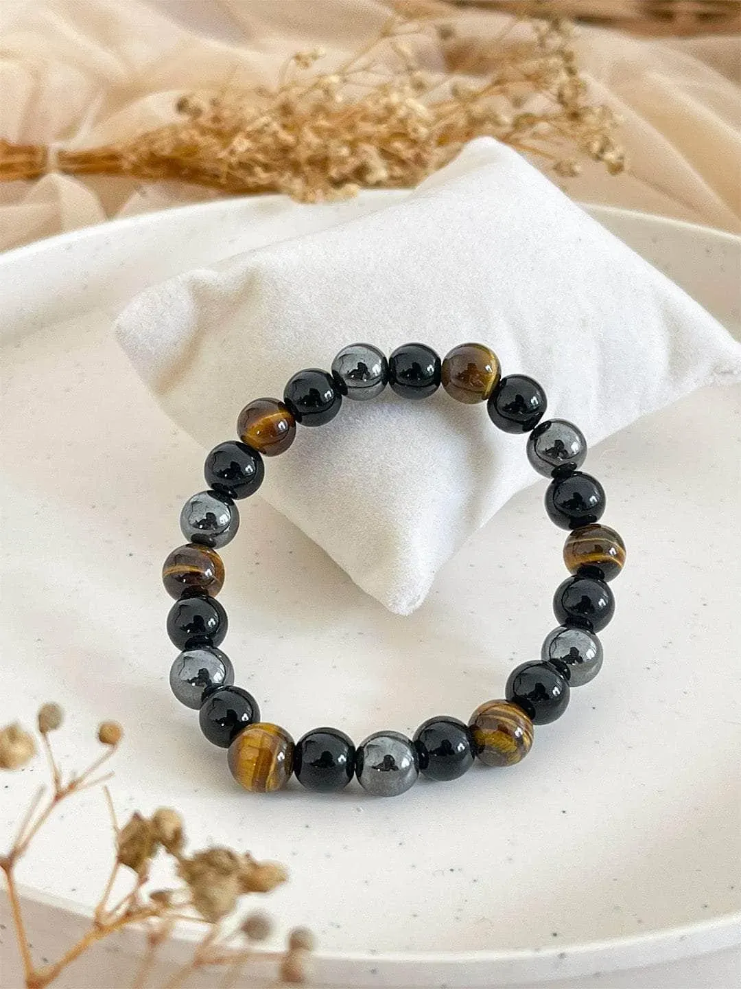 Triple Protection Bracelet with tiger eye, black and hematite beads on a white cushion